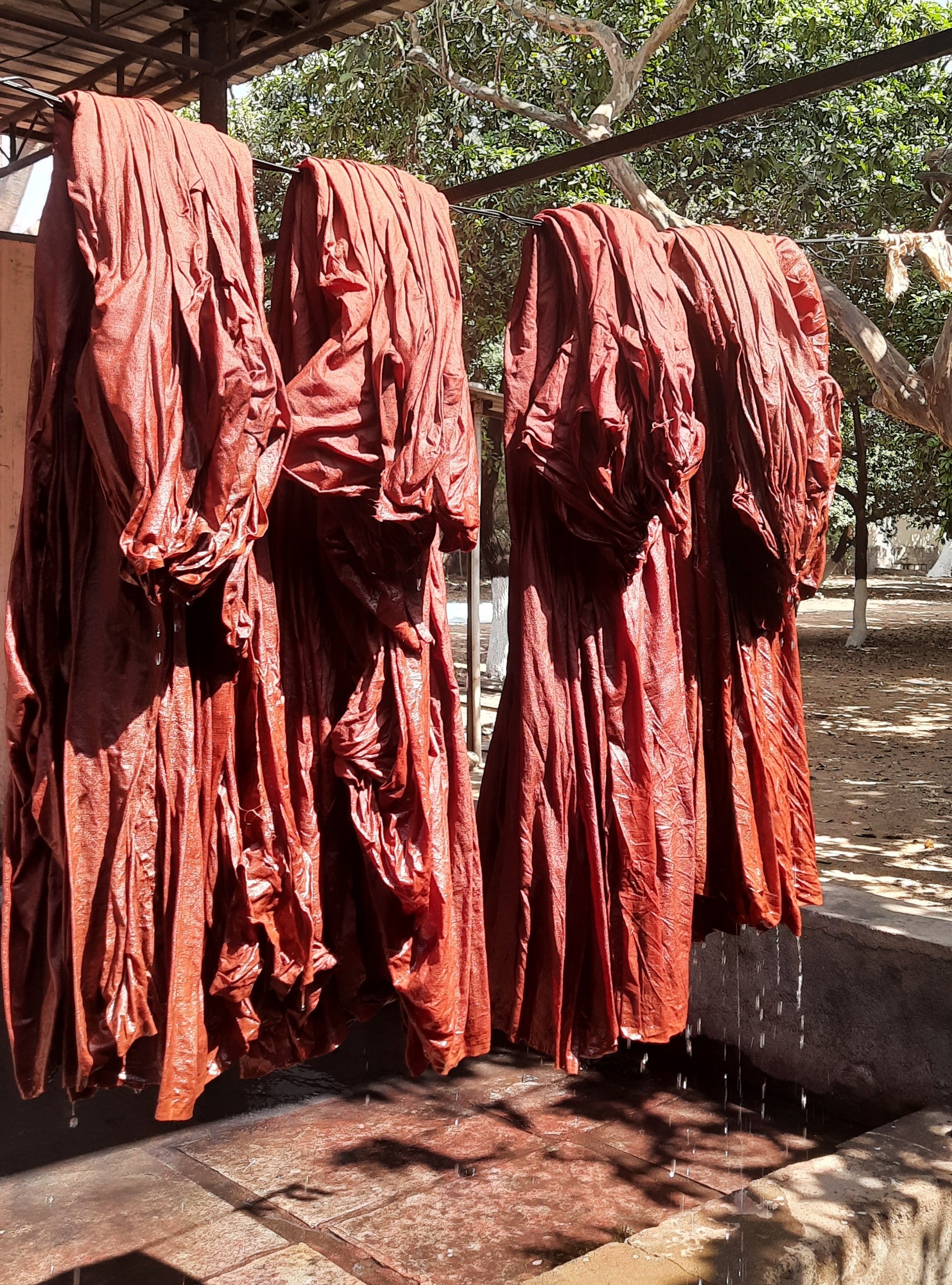 Red fabric hanging on a wooden rack outdoors